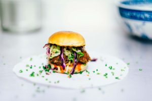 a small burger with purple and green garnish